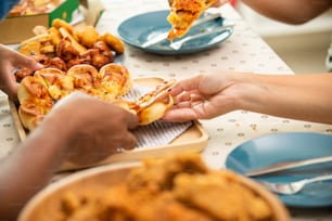 Happy African family parents and two little daughter eating fried chicken and pizza for dinner together. Father and mother and cute child girl kid enjoy and fun eating and sharing a meal together at home