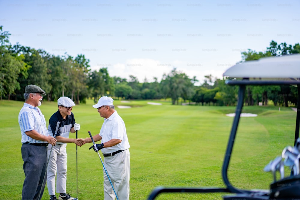 Group of Asian people businessman and senior CEO enjoy outdoor sport lifestyle golfing together at golf country club. Healthy men golfer shaking hand after finish talking business project and game on golf course
