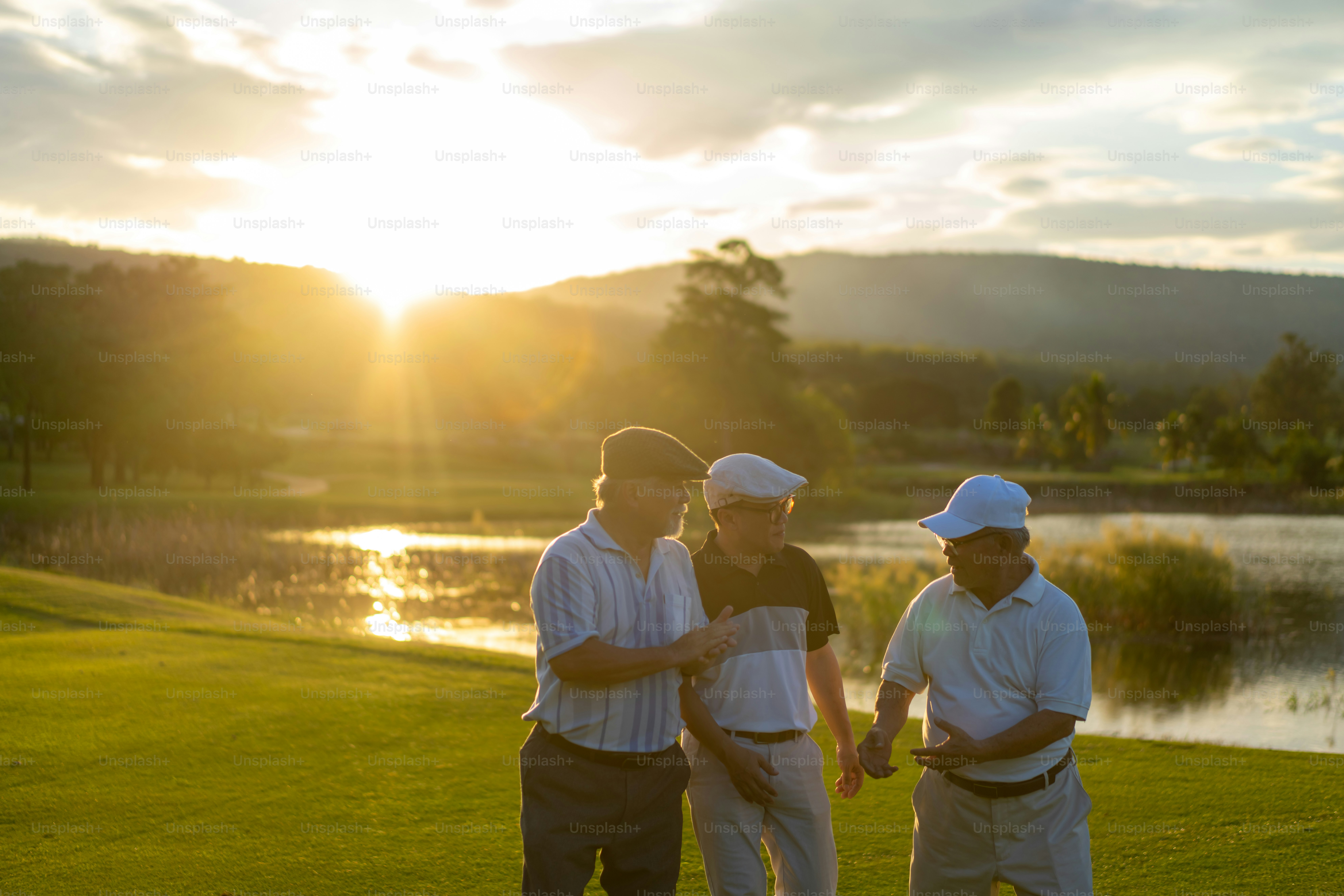 Trois hommes en chapeaux discutant sur un terrain de golf pendant l’heure dorée