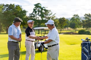 4K Group of Asian people businessman and senior CEO enjoy outdoor sport lifestyle golfing together at golf country club. Healthy men golfer shaking hand after finish the game at golf course on summer vacation