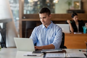 Hombre de negocios sentado trabajando en una computadora portátil en la oficina.