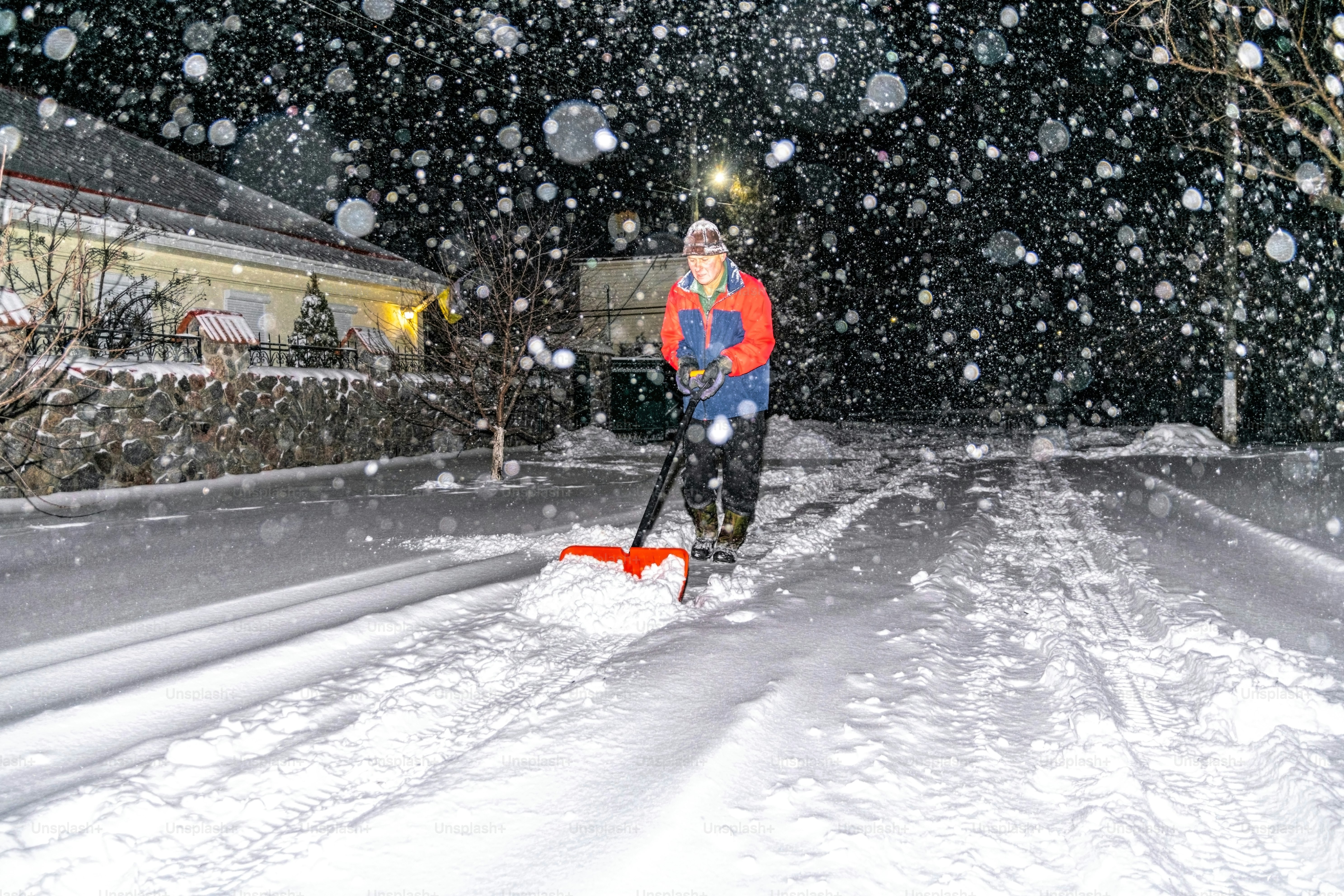 elderly man with a shovel in his hands clears the street after a heavy snowfall. Man at seasonal work