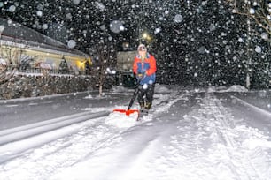 Uomo anziano con una pala in mano sgombera la strada dopo una forte nevicata. Uomo al lavoro stagionale