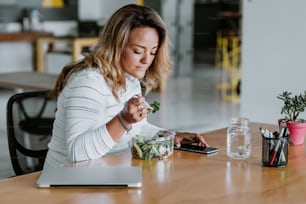 latin adult woman eating salad lunch at the office in Mexico Latin America