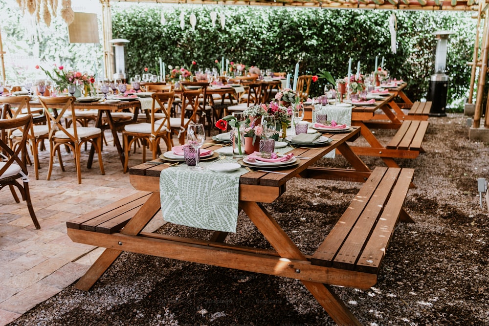 라틴 아메리카의 결혼식 피로연을 위해 장식된 테이블에 꽃과 접시가 있는 테이블이 있는 테라스