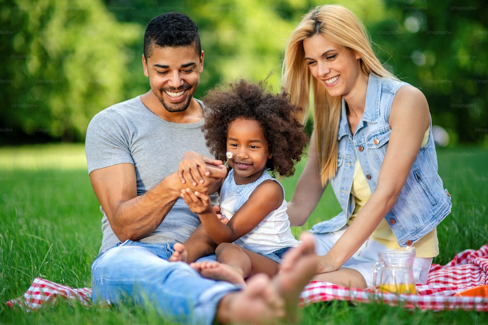 Glückliche junge multiethnische Familie, die ein Picknick in der Natur genießt