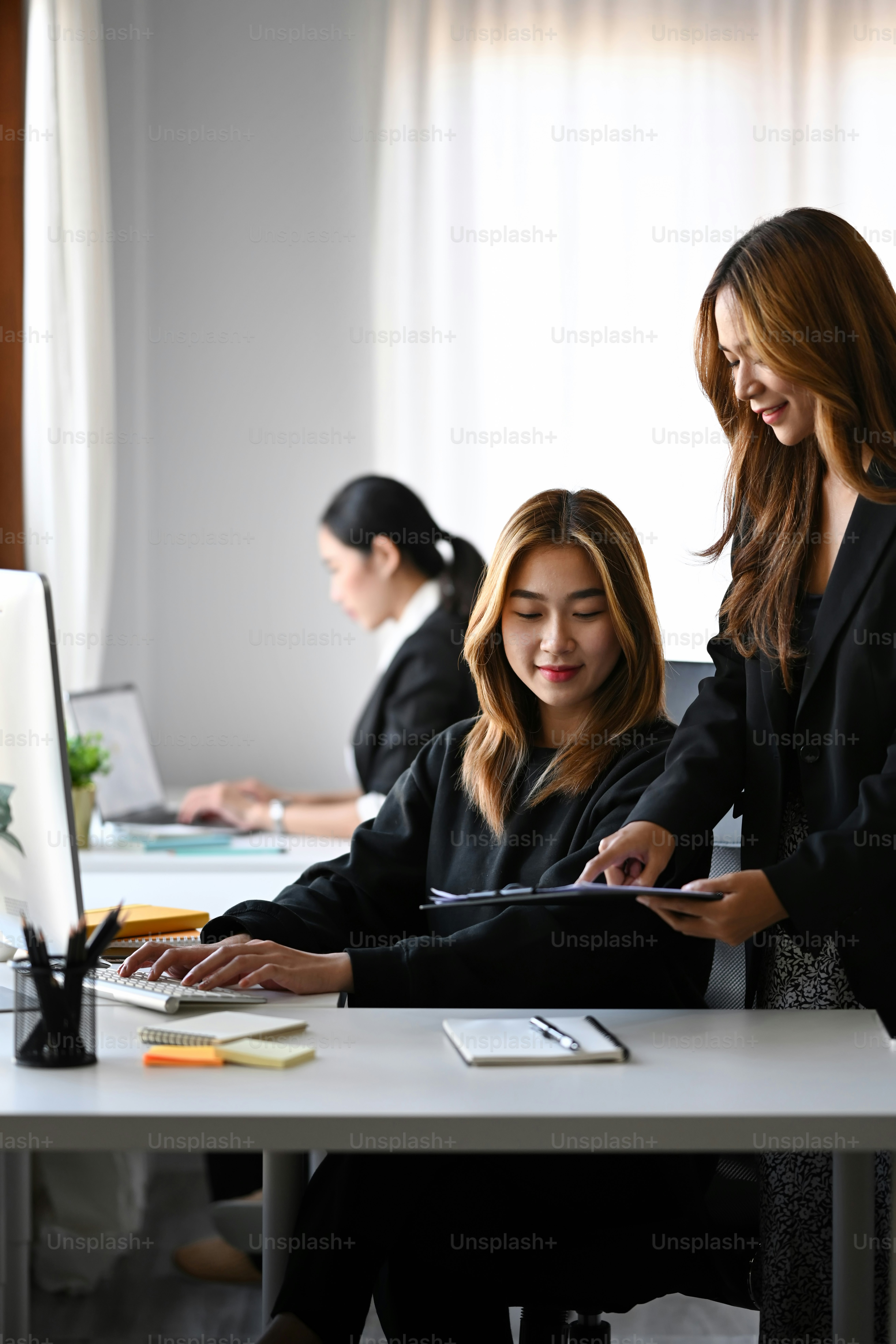 オフィスで一緒に働く2人のアジア人ビジネスウーマン。