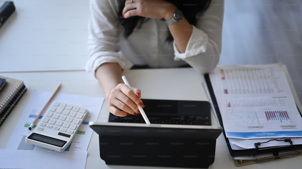 Businesswoman analyzing financial data on computer tablet.