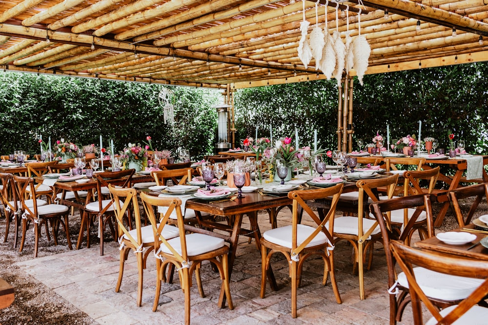 라틴 아메리카의 결혼식 피로연을 위해 장식된 테이블에 꽃과 접시가 있는 테이블이 있는 테라스