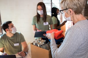Gruppe von Freiwilligen mit Gesichtsmaske, die im gemeinnützigen Spendenzentrum der Gemeinde arbeiten.