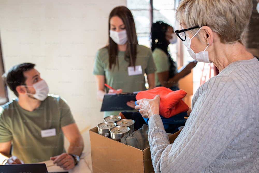 Grupo de voluntarios con mascarilla trabajando en un centro de donación de caridad comunitaria.