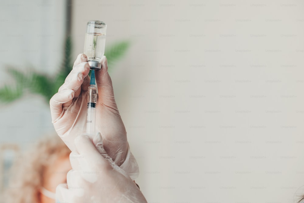 Mãos do médico segurando uma seringa com vacina contra o coronavírus. Vacinação contra a Covid-19. Tratamento médico. Proteção contra vírus.