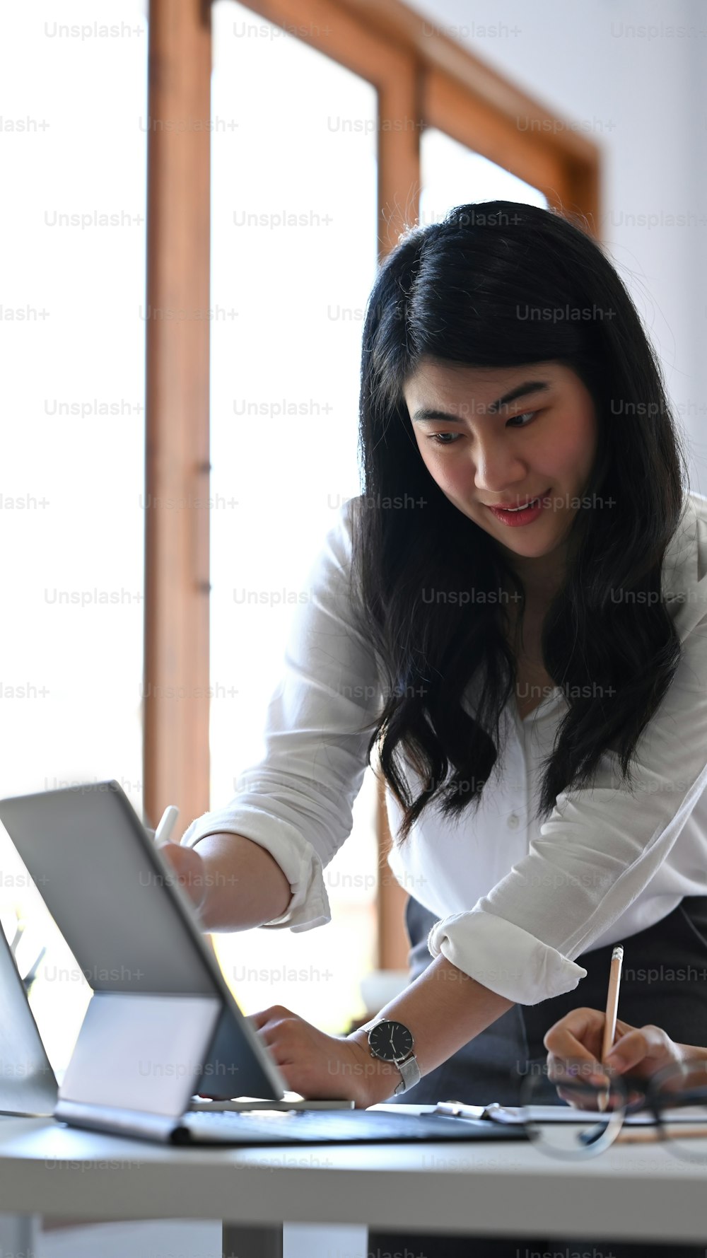 Empresaria asiática compartiendo ideas o plan de negocios de inicio en una tableta de computadora con su colega.