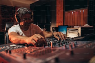 Productor musical hispano senior trabajando en una caja de resonancia de mezclas mientras está en su estudio