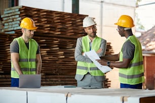 Des employés d’entrepôt et leur gestionnaire discutent tout en analysant la paperasse au département du bois d’œuvre.