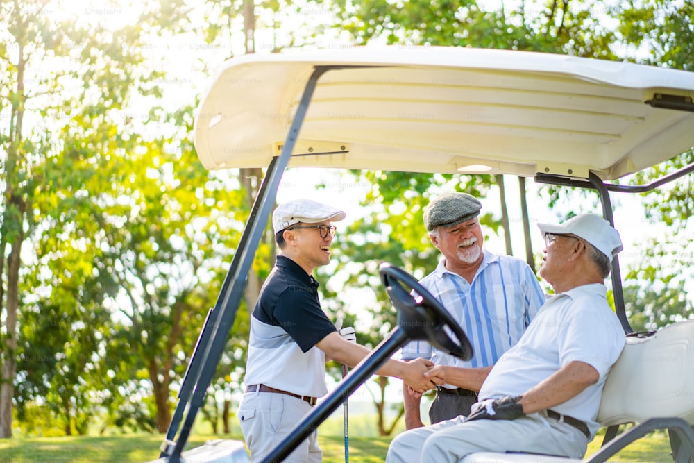 Group of Asian people businessman and senior CEO enjoy outdoor activity lifestyle sport golfing together at country club on summer vacation. Healthy male golfer sitting golf cart with talking together