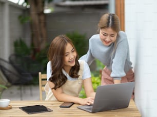 뒤뜰에서 노트북 컴퓨터로 과제를 하고 있는 두 명의 아시아 젊은 여대생.