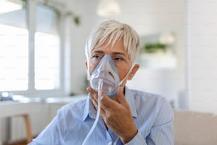 산소 마스크 흡입, 폐렴 코로나바이러스 전염병에 아픈 노인 여성. 산소 마스크를 쓰고 치료를 받고 있는 아픈 노인 여성. COVID 19에 걸린 노인 여성