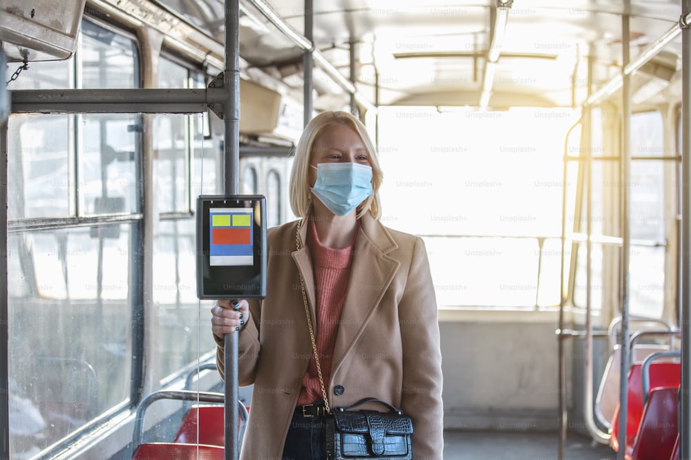 Woman With Protective Face Mask In Bus Transport. Young woman wearing protective face mask, she standing in bus transportation in the city. Woman with mask in bus