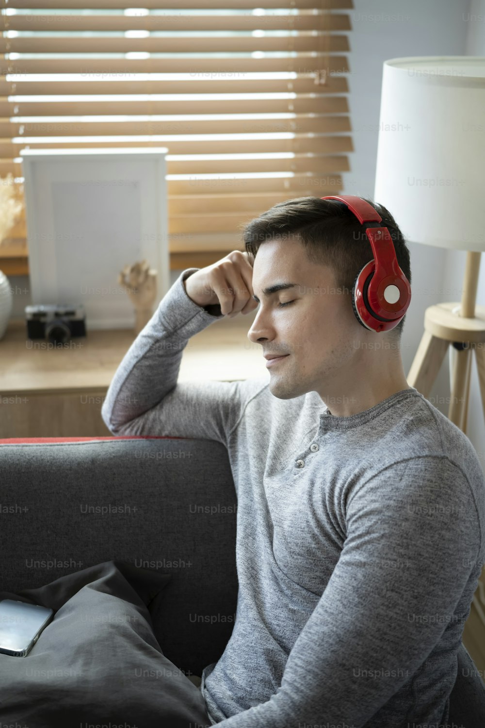 Relaxed young man listening to music with headphone on sofa.