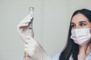 Close-up portrait of a nurse dials the vaccine into a syringe. Corona virus immunization.