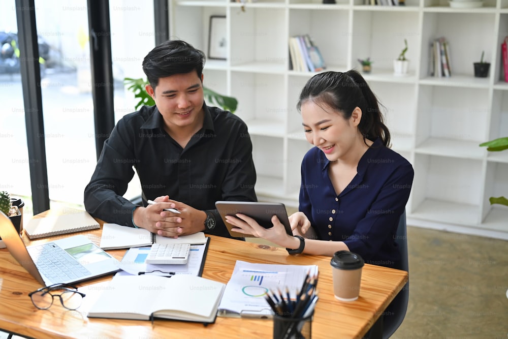 Smiling businesswoman using a digital tablet and discussing information with colleague.