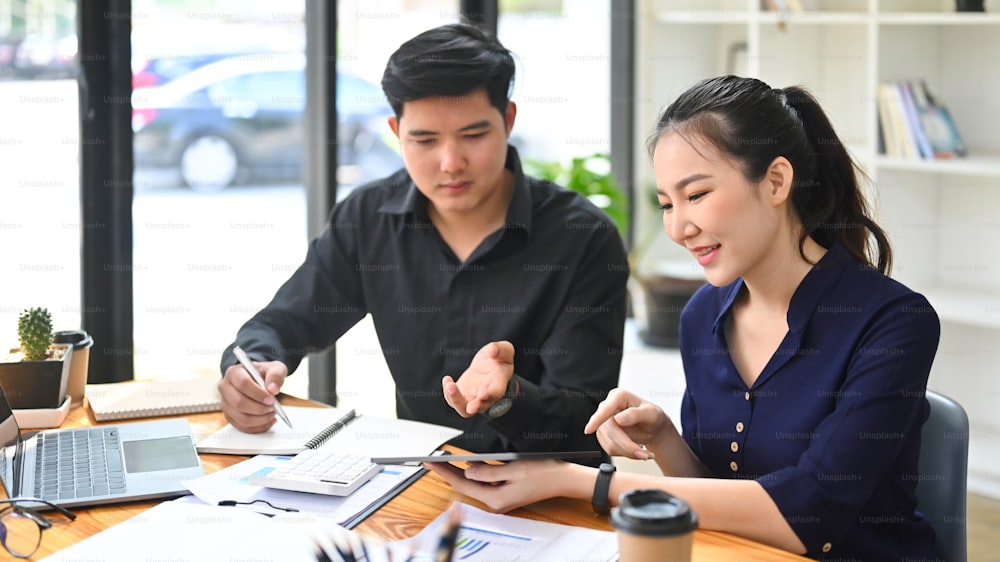 Two young businesspeople working together in bright office.