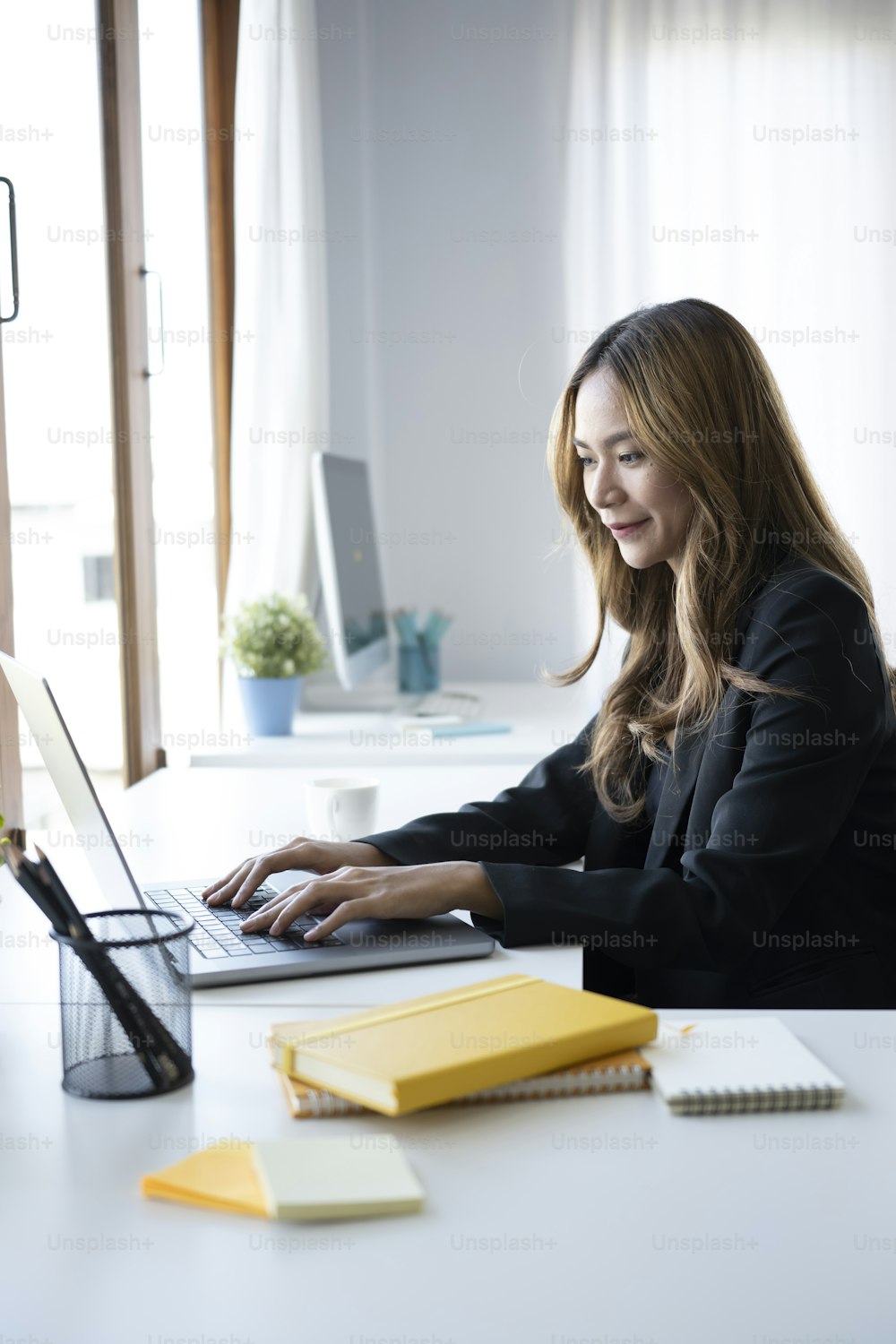 Charming businesswoman sitting in bright modern office and working with laptop.