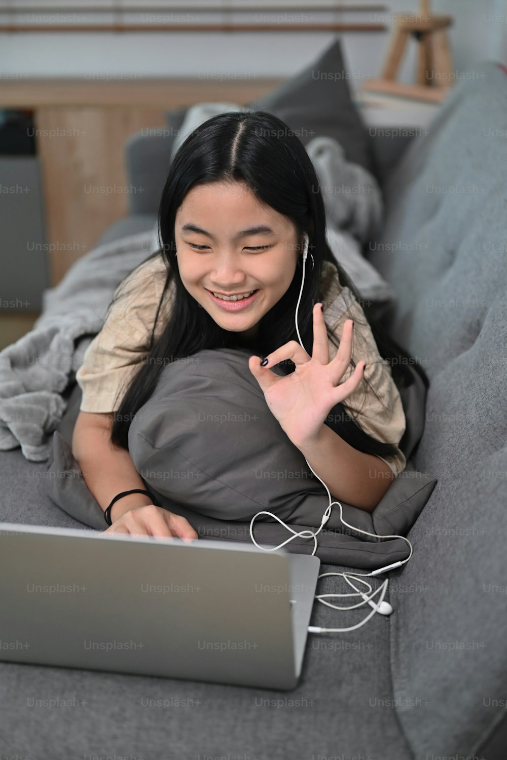 웃고 있는 아시아 소녀는 집에서 컴퓨터 노트북으로 화상 통화를 하고 있다.