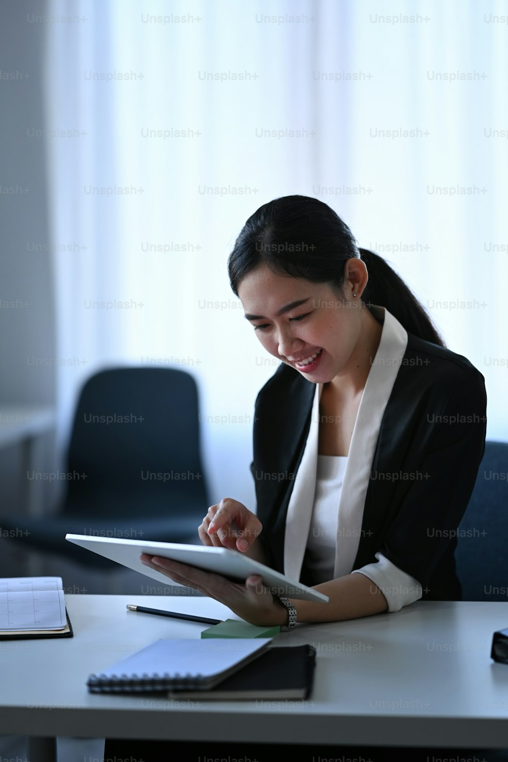 Empresária sorridente verificando informações em tablet digital.