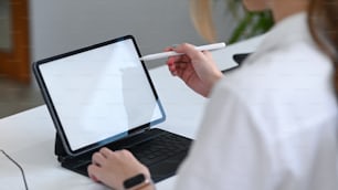 Young businesswoman holding stylus pen writing on screen of computer tablet.