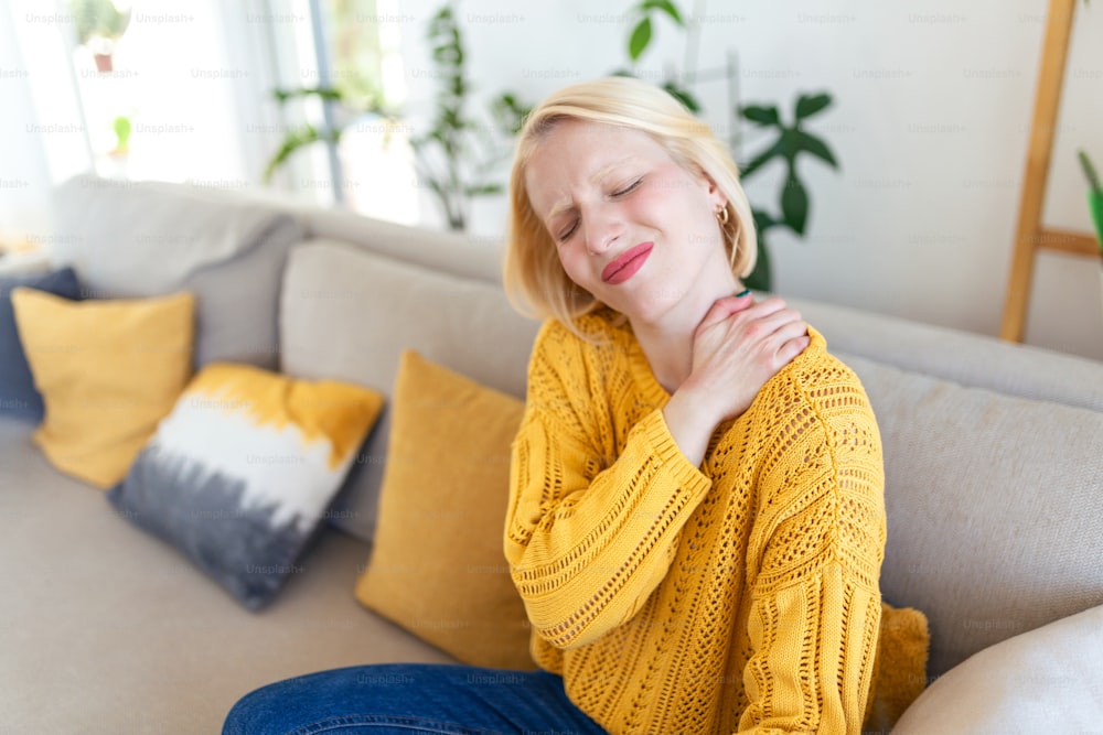 Pain in the shoulder. Upper arm pain, People with body-muscles problem, Healthcare And Medicine concept. Attractive woman sitting on the bed and holding painful shoulder with another hand.