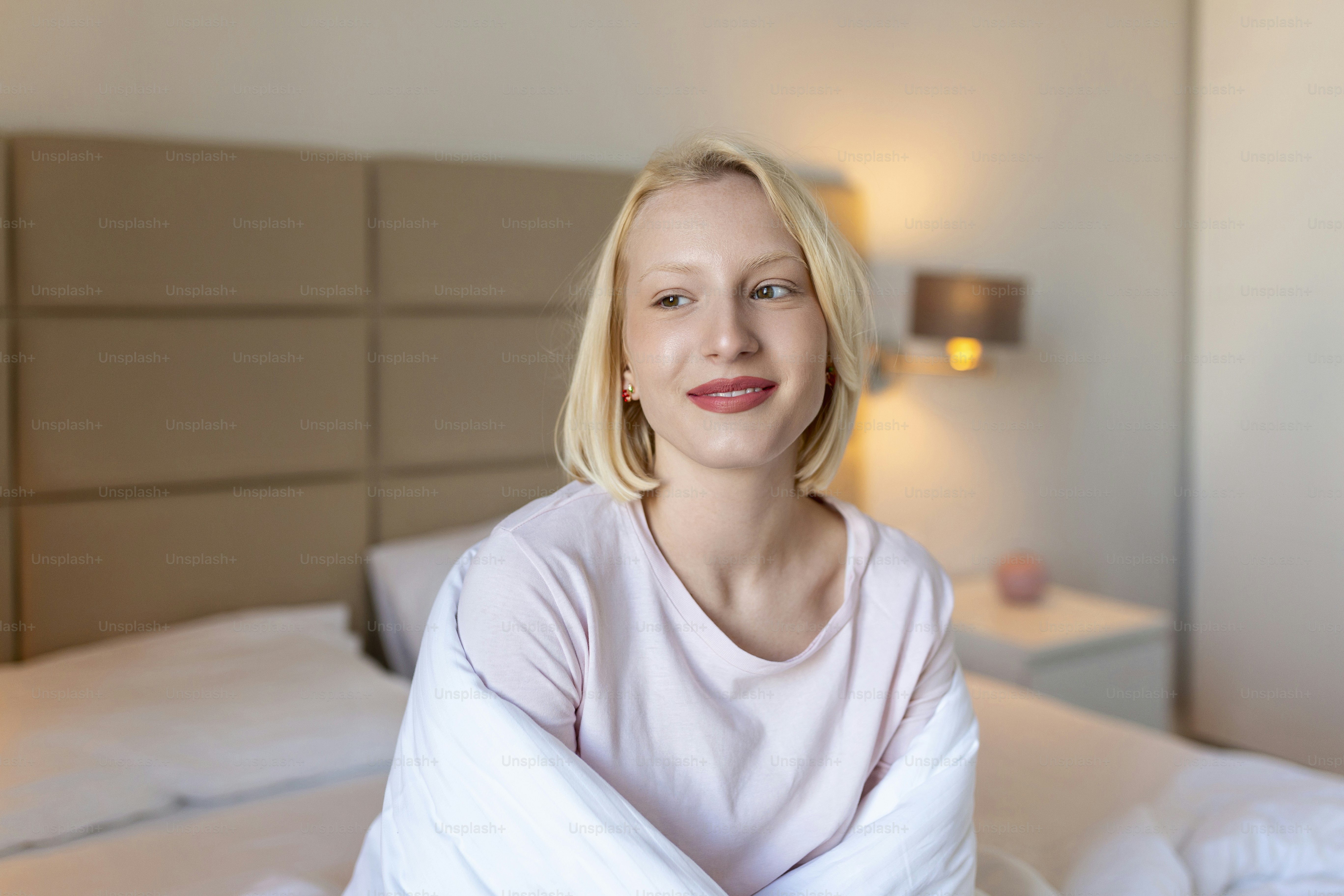 目覚めた後、毛布に包まれた女性は、ぐっすり眠った後、幸せでリラックスした一日に入ります。甘い夢、おはようございます、新しい日、週末、休日のコンセプト