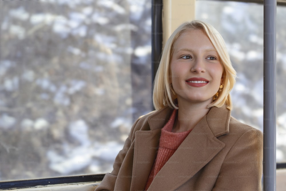 Commuter daydreaming on bus. Portrait of a woman inside a bus. Happy bus passenger traveling sitting in a seat and looking through the window. Portrait of smiling woman passenger sitting in public bus