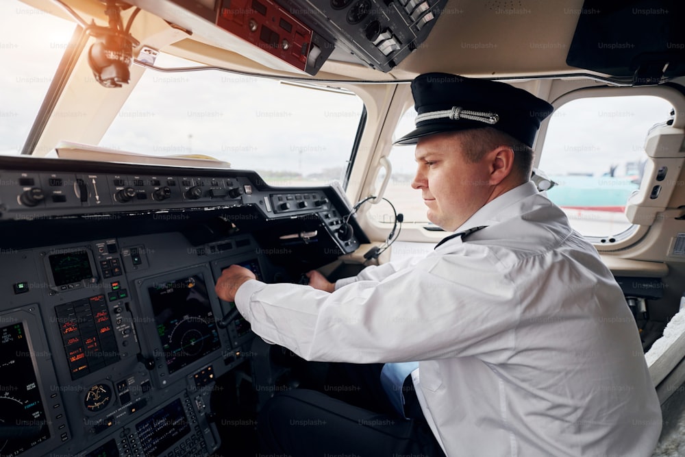 Professioneller Arbeiter. Der Pilot in formeller Kleidung sitzt im Cockpit und steuert das Flugzeug.