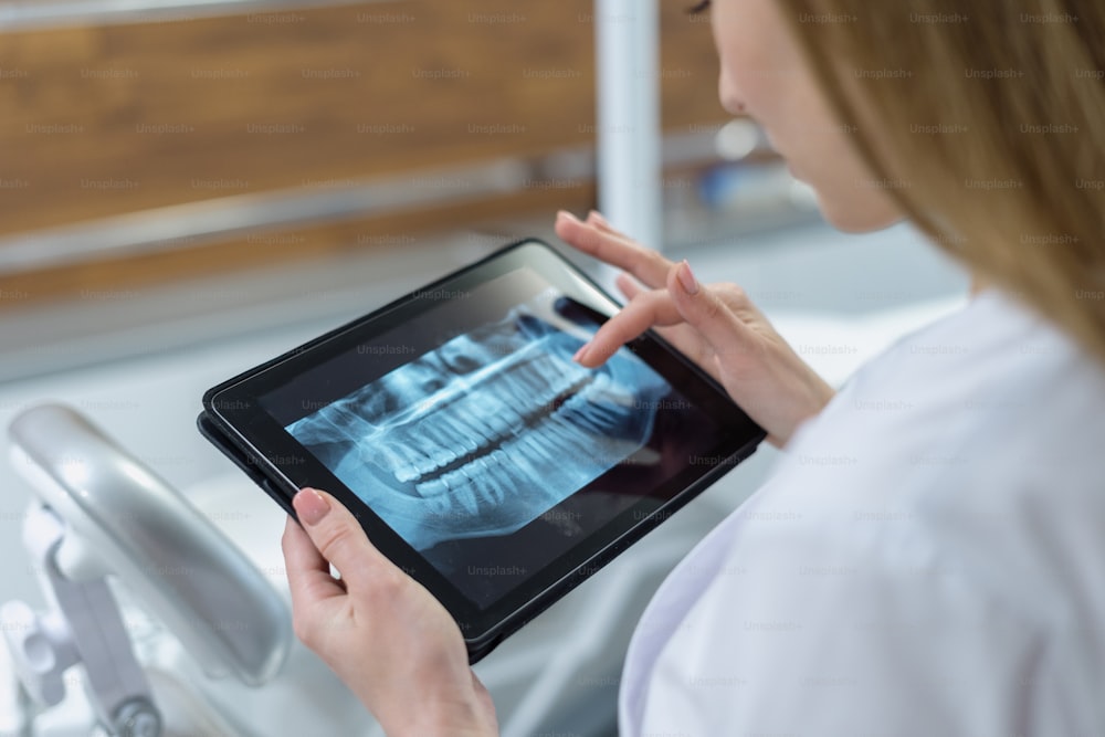 Vista laterale del medico con tablet e immagine radiografica dentale panoramica. Scansione ortopantomografica. Tecnologia moderna in odontoiatria. Concetto ortodontico