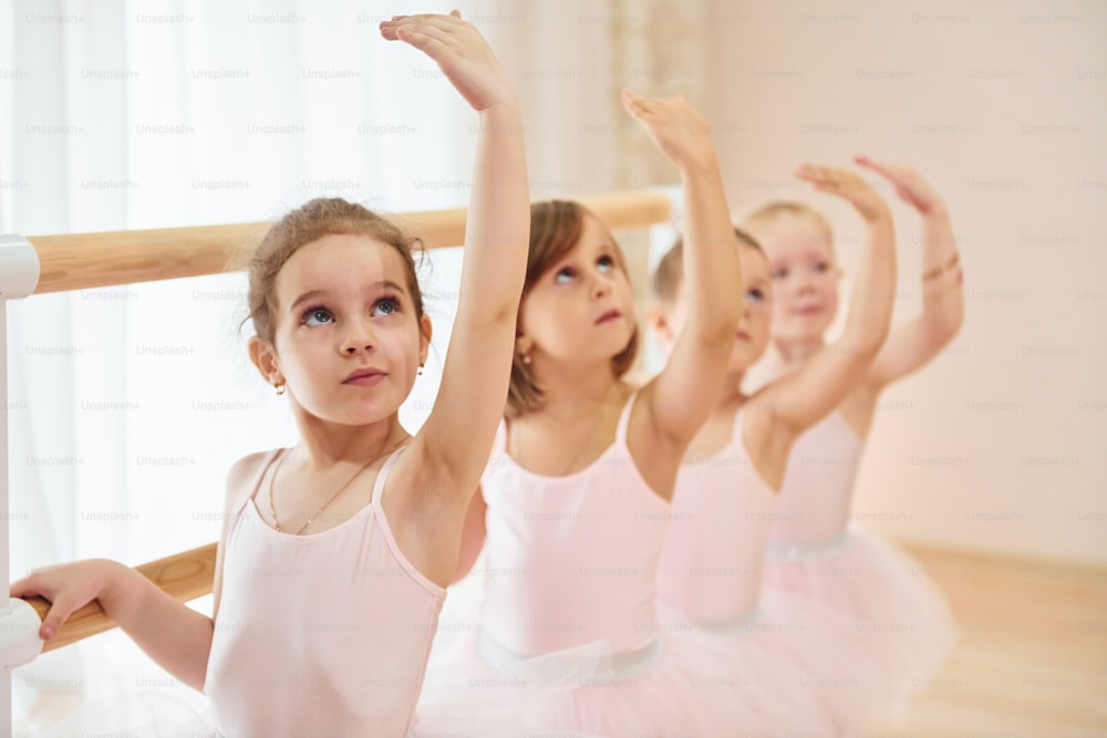 Kleine Ballerinas bereiten sich auf die Aufführung vor, indem sie Tanzbewegungen üben.
