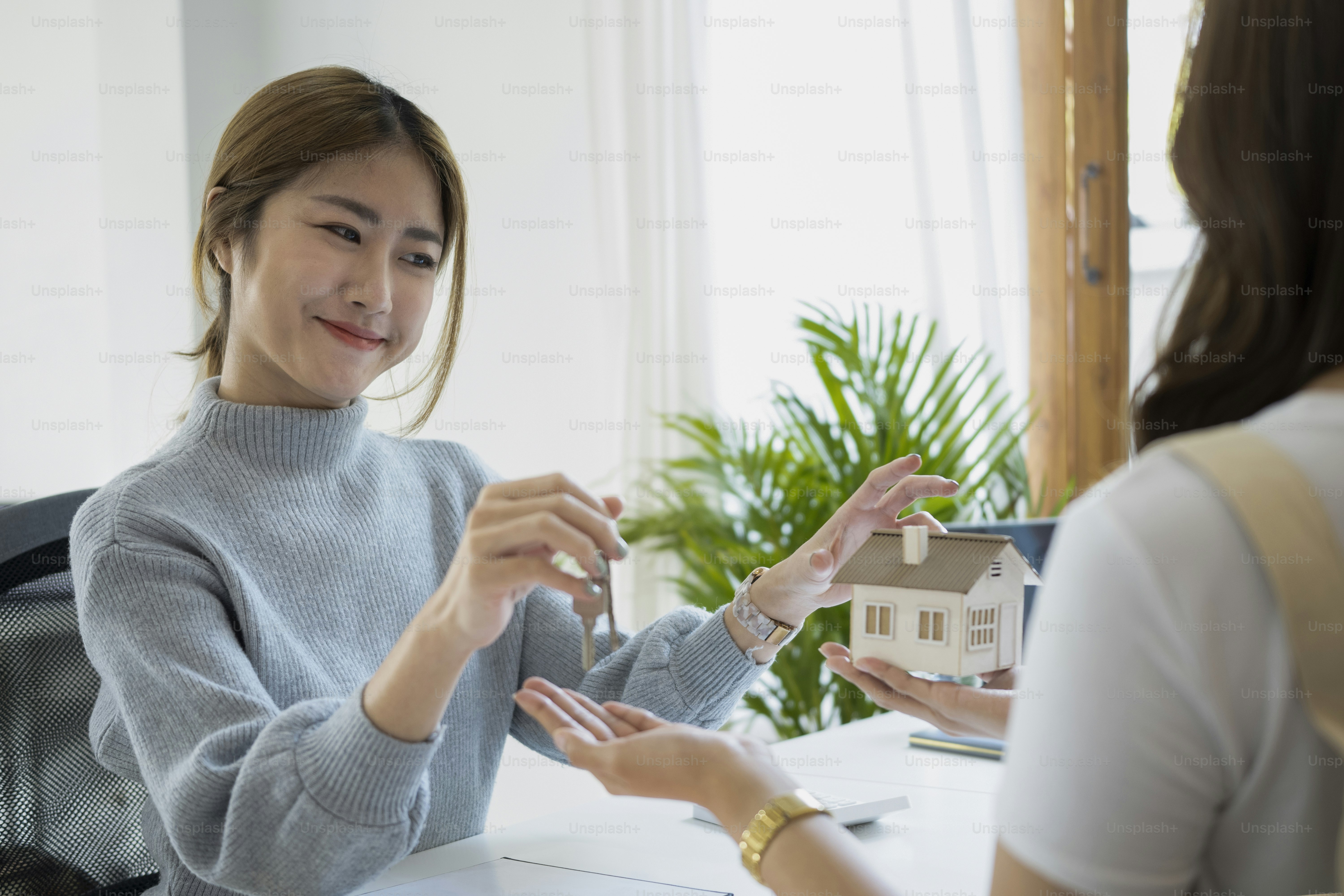 Agente imobiliário sorridente dando as chaves da casa ao cliente após a assinatura do contrato.