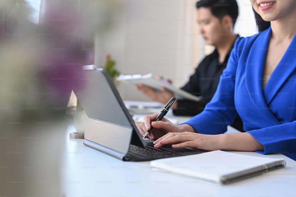 Cropped shot smiling business woman sitting in meeting room and using computer tablet.