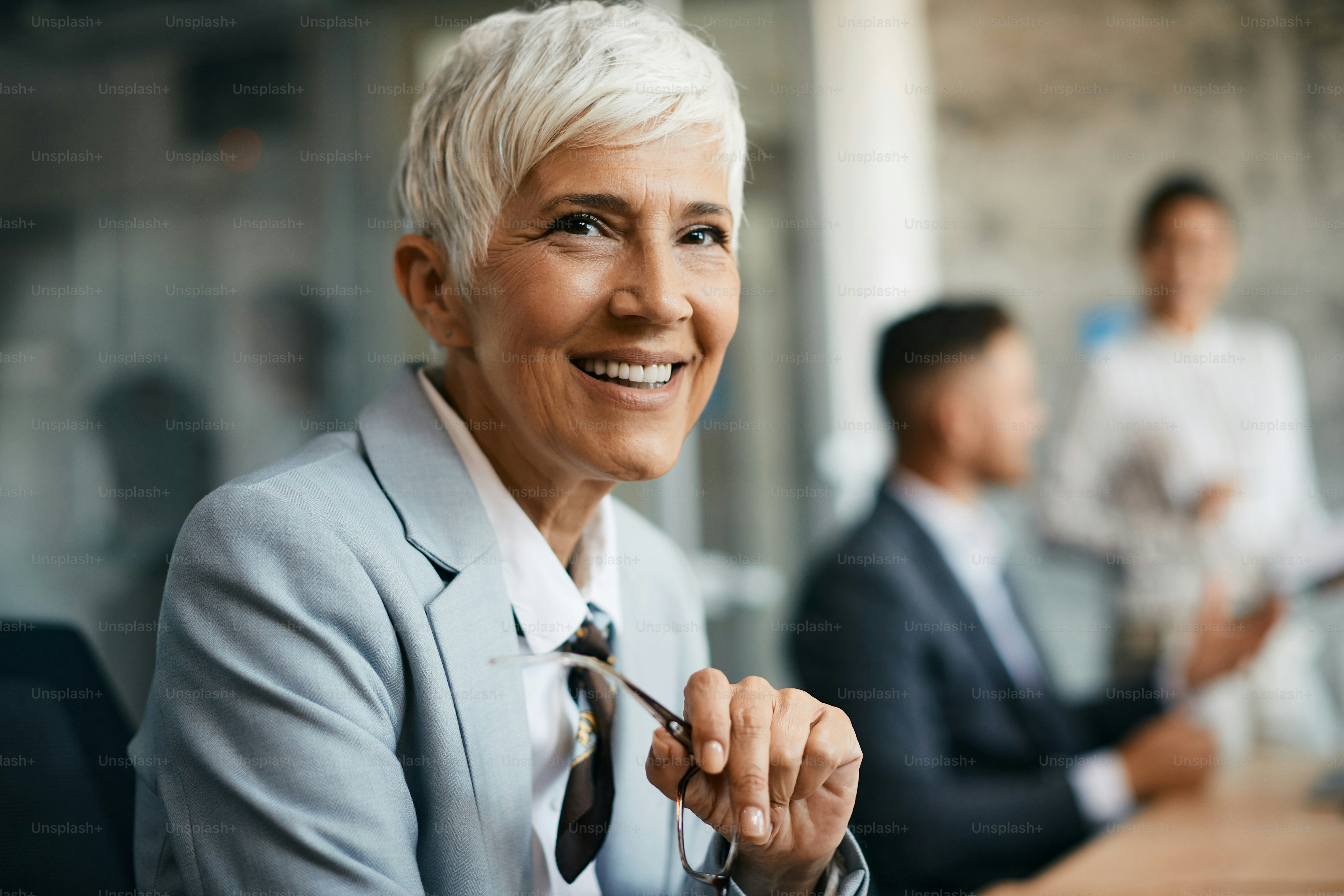 Portrait of happy mature CEO working in her office and looking at ...