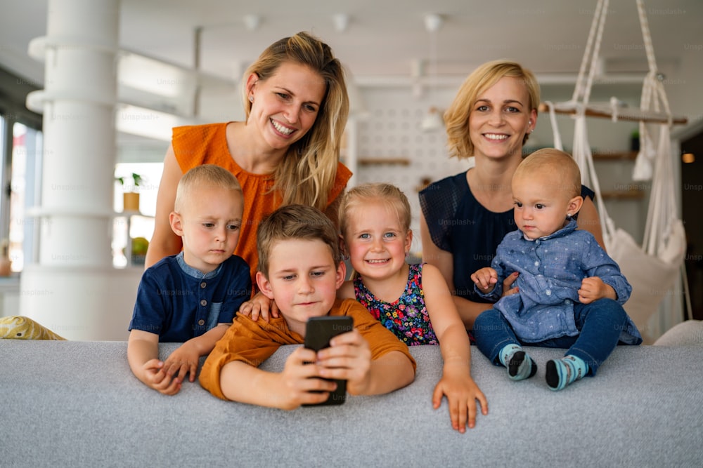 Portrait of happy big family. Gay couple of women smiling and having fun with her children at home