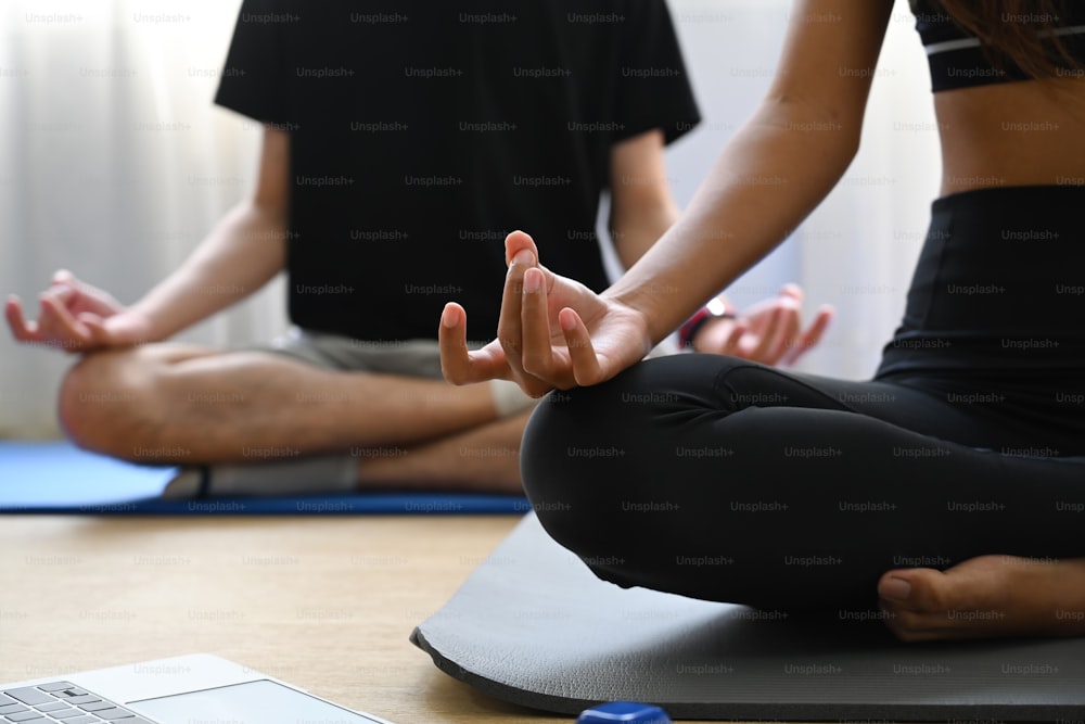 Jovem casal pacífico praticando yoga em pose de lótus na sala de estar.