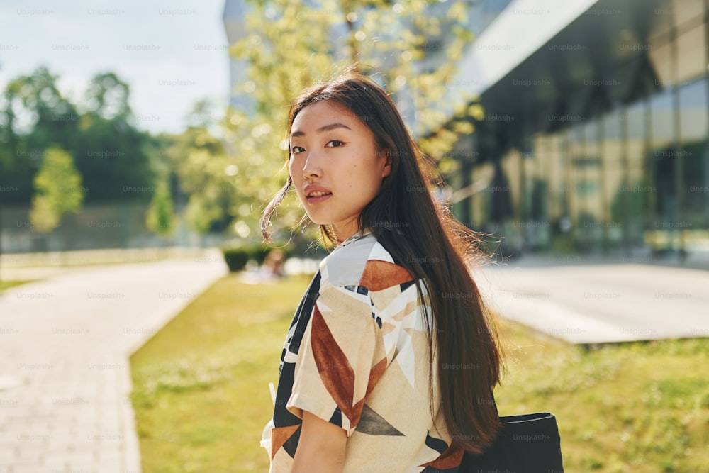 Student walks near modern building. Young asian woman is outdoors at  daytime. photo – Fashion Image on Unsplash
