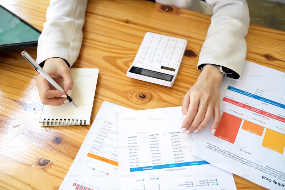 Vista superior de um contador ou trabalhador financeiro analisando dados financeiros sobre a papelada em seu escritório.