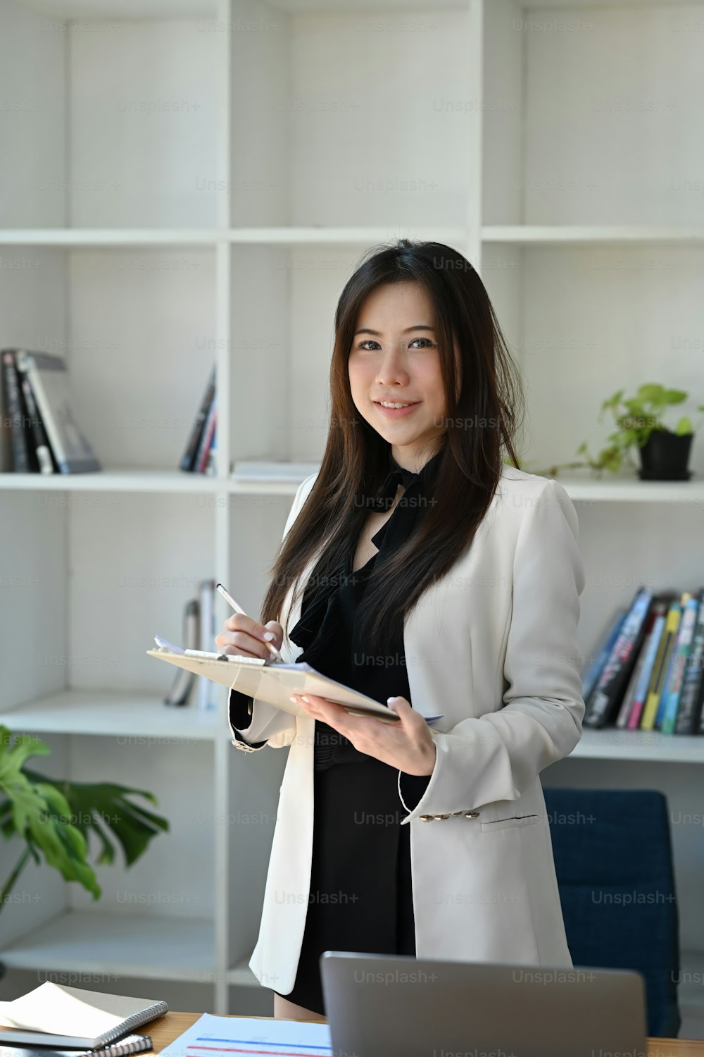 Portrait of confident businesswoman standing at her office desk and looking at camera.