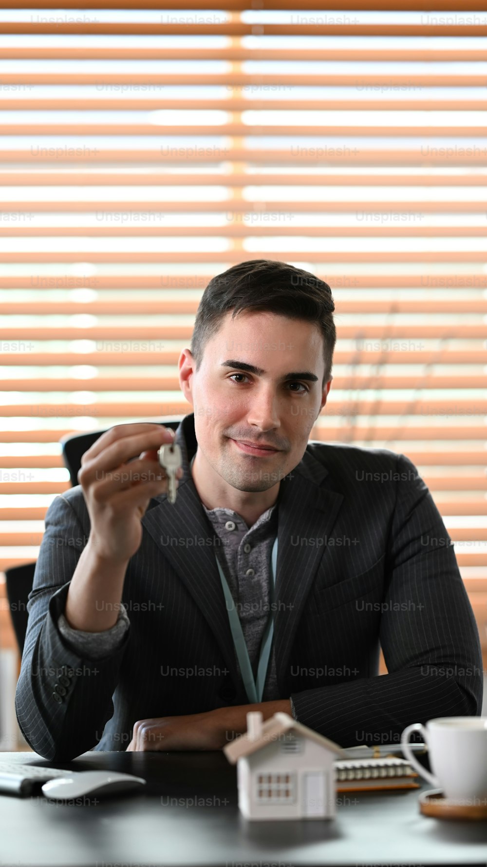 Portrait estate agent holding house key and smiling to camera. Insurance or loan real estate concept.