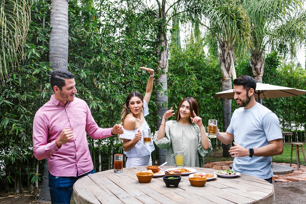 Group of Young latin Friends Meeting For beer, michelada Drinks And mexican Food Making A Toast In Restaurant terrace in Mexico Latin America