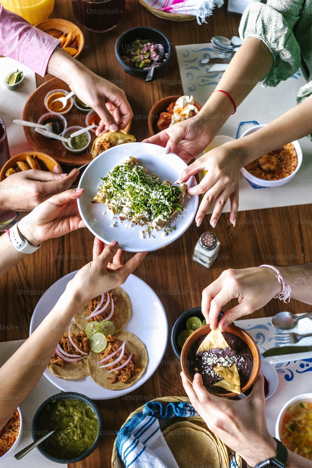 gruppo di amici latini che mangiano tacos messicani e cibo tradizionale, spuntini e persone mani sopra il tavolo, vista dall'alto. Cucina messicana America Latina