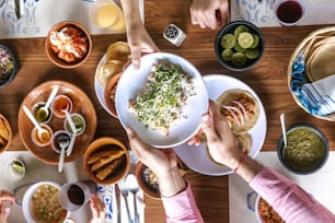 group of latin Friends eating Mexican Tacos and traditional food, snacks and peoples hands over table, top view. Mexican cuisine Latin America