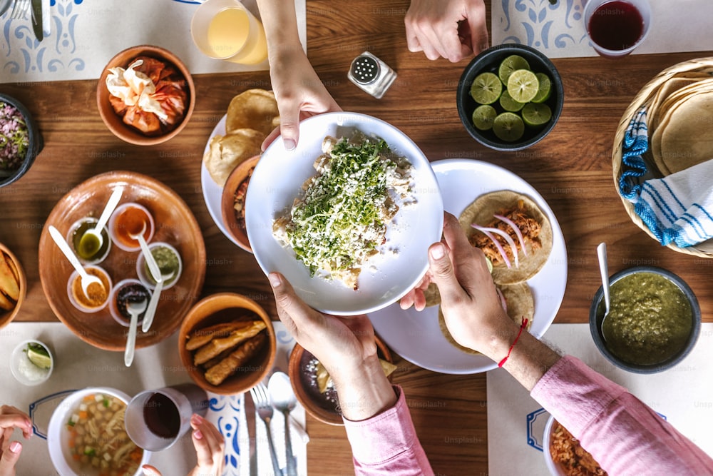 grupo de amigos latinos comendo tacos mexicanos e comida tradicional, lanches e povos mãos sobre a mesa, vista superior. Culinária mexicana América Latina